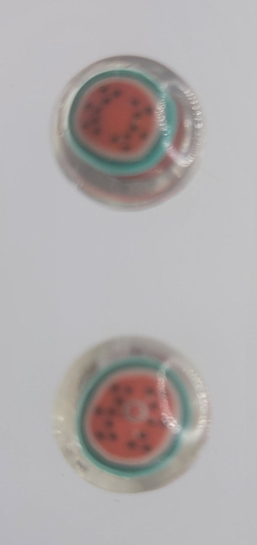 Round earrings with watermelon design on a light gray background