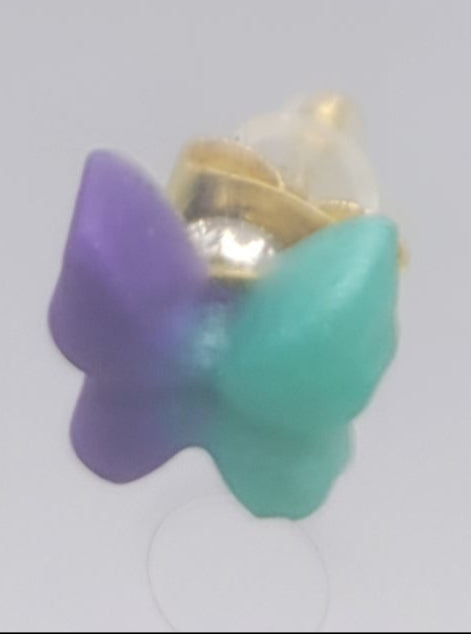 Butterfly-shaped earrings with purple and teal wings on a light gray background