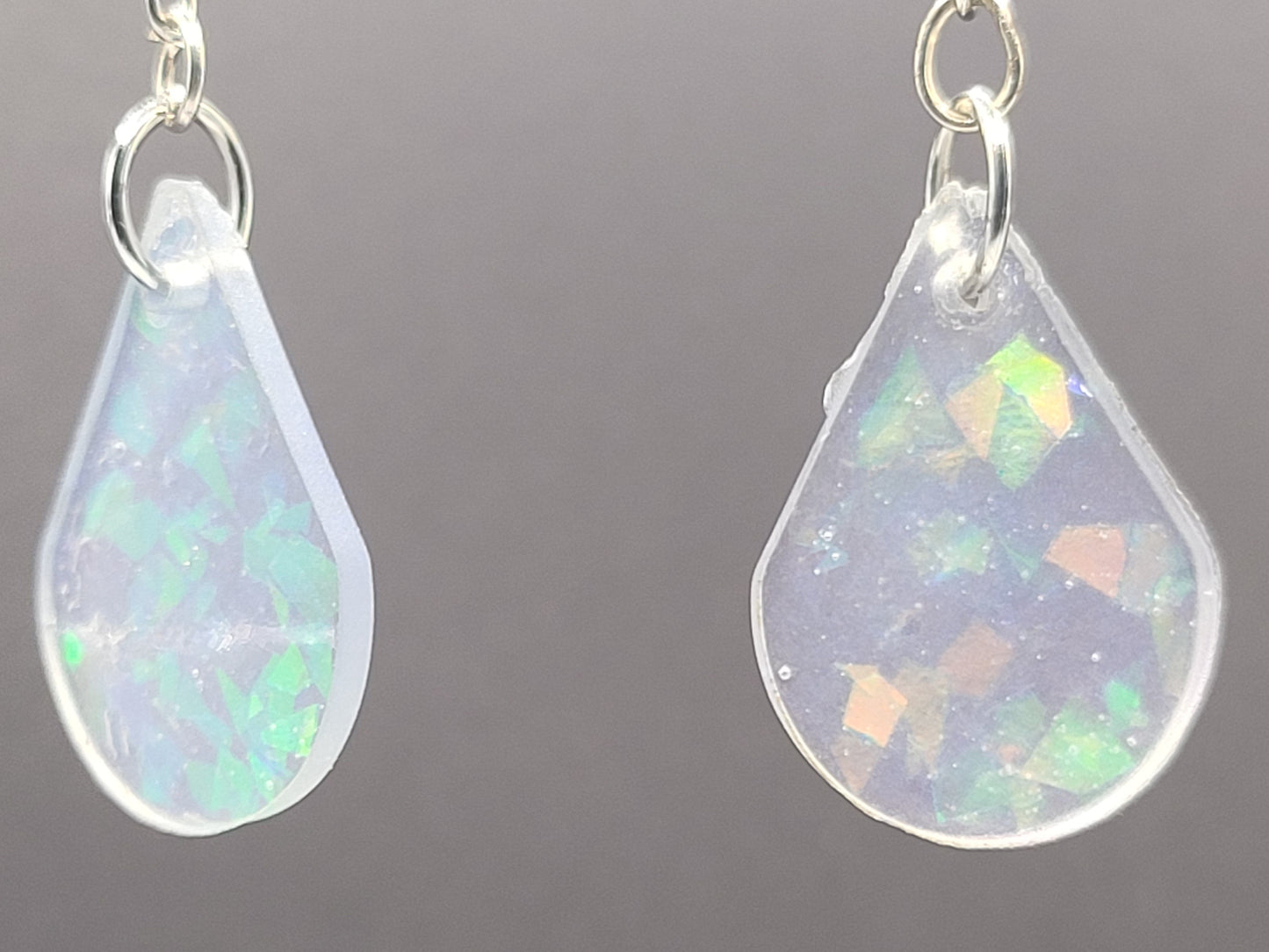 Teardrop-shaped opal earrings on a gray background