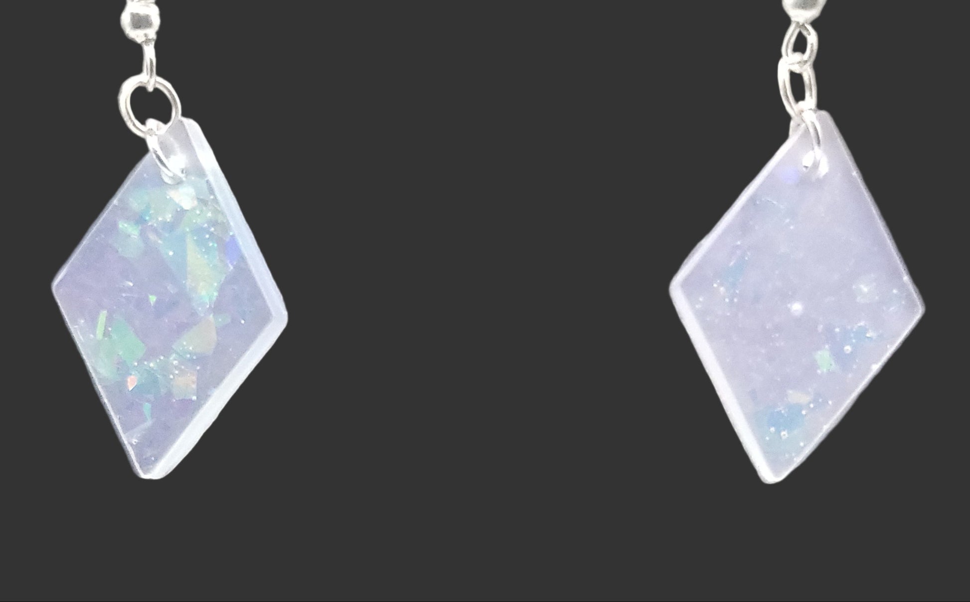 Diamond-shaped earrings with a reflective surface, opal on a gray background
