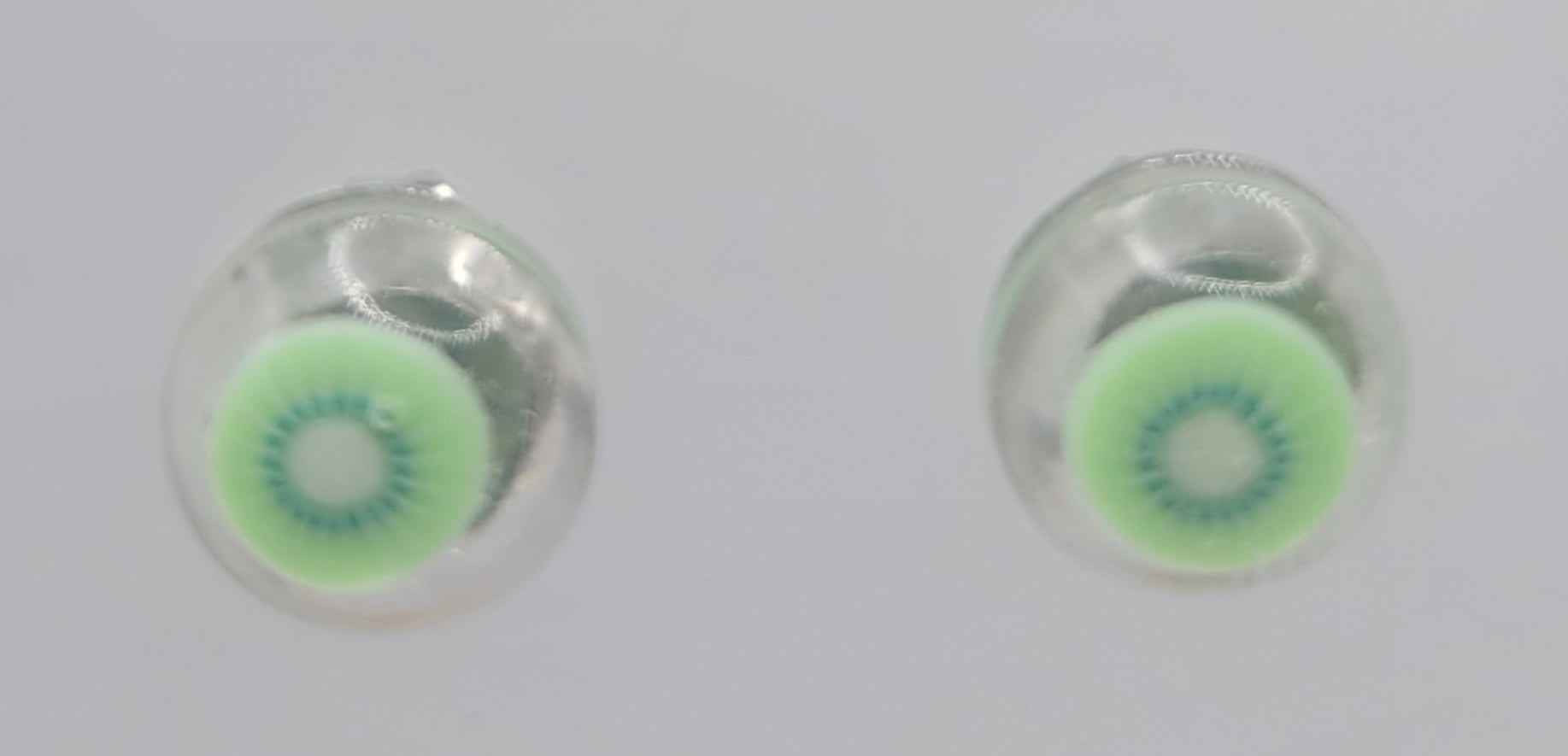 Set of colorful round earrings on a clear display stand.