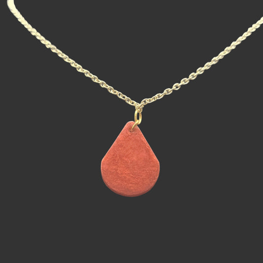 Red swirling colored teardrop shaped pendant on a gold chain