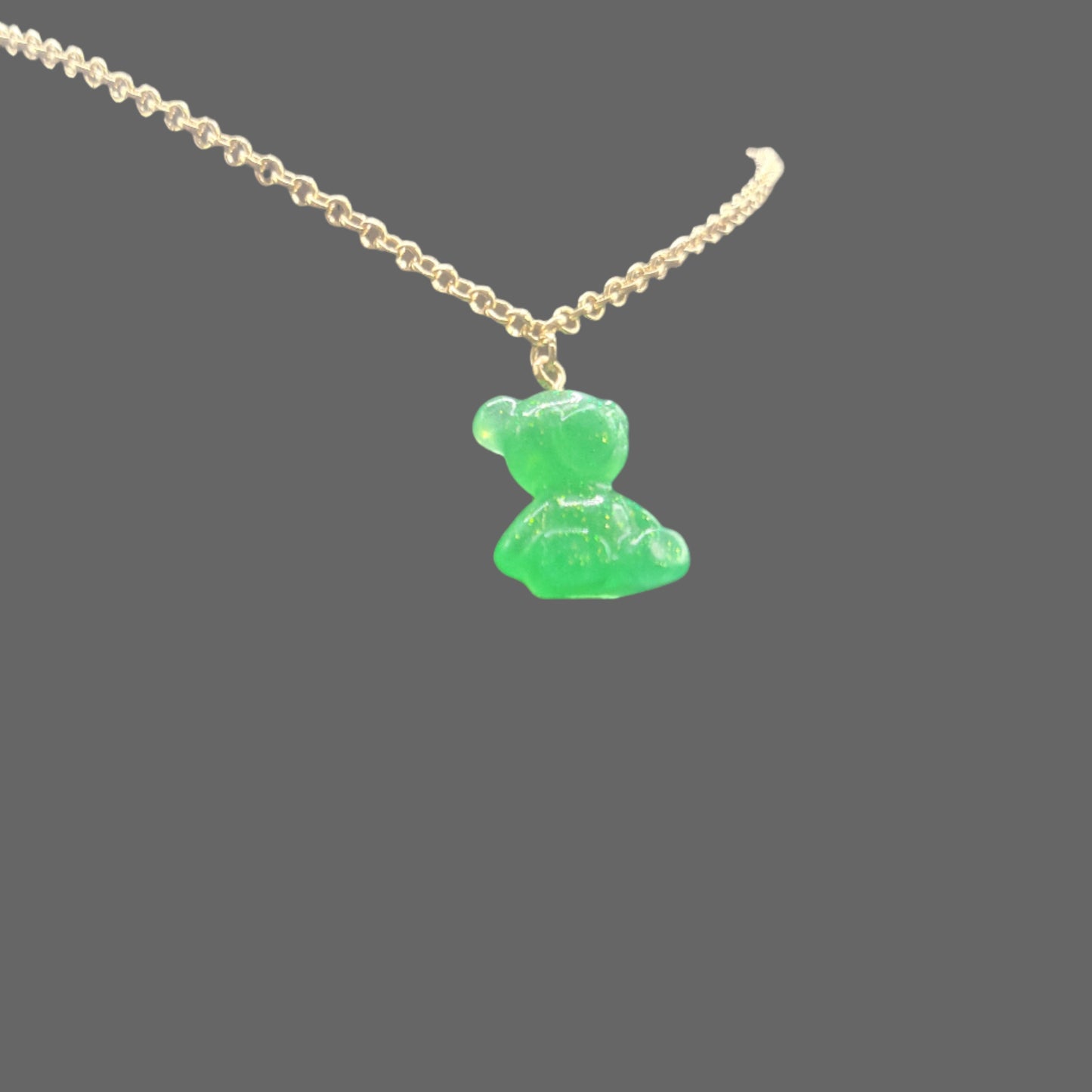 Green bear-shaped pendant on a gold chain against a black background