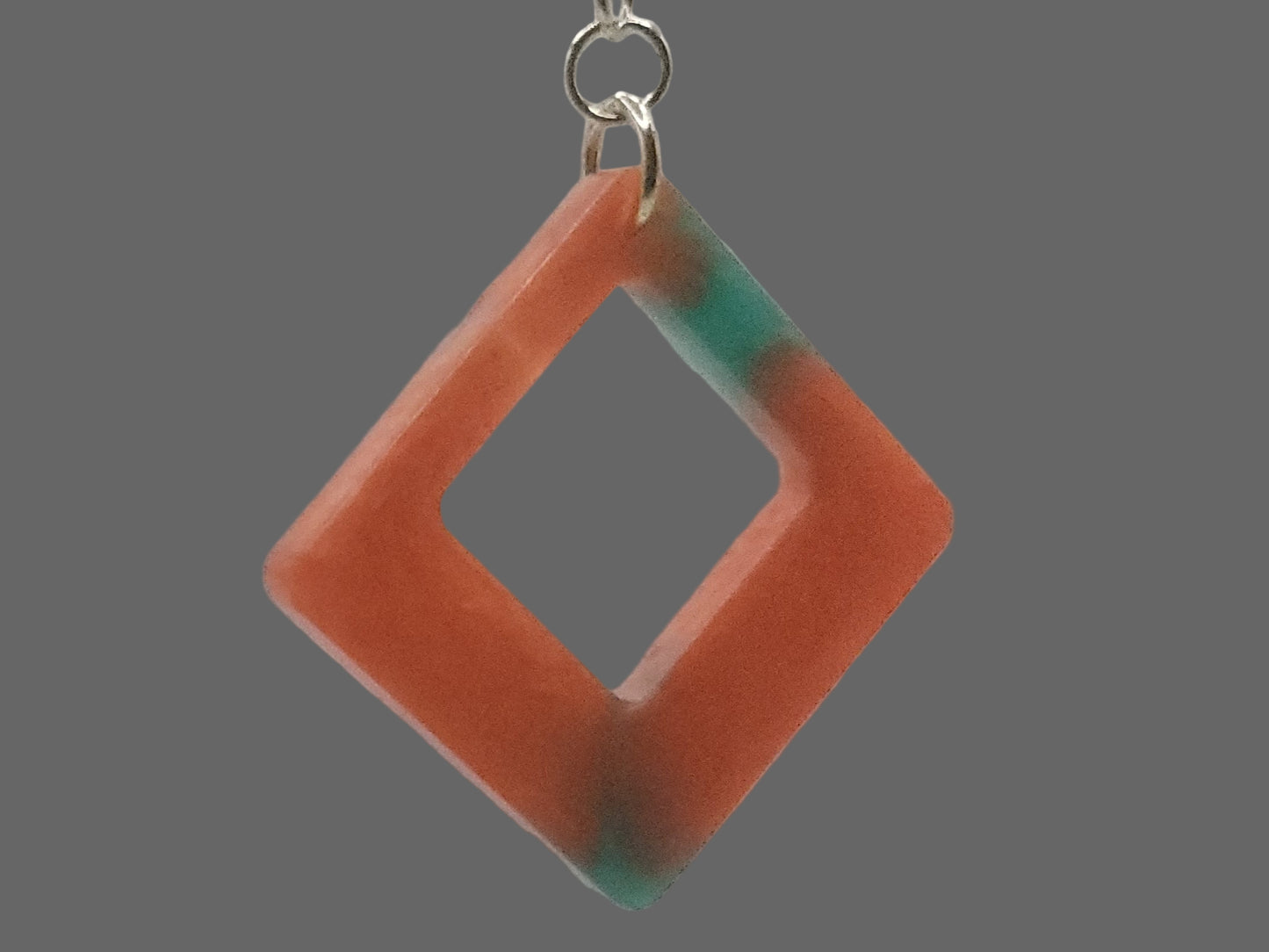 Geometric pendant earring with a square cutout on a plain background