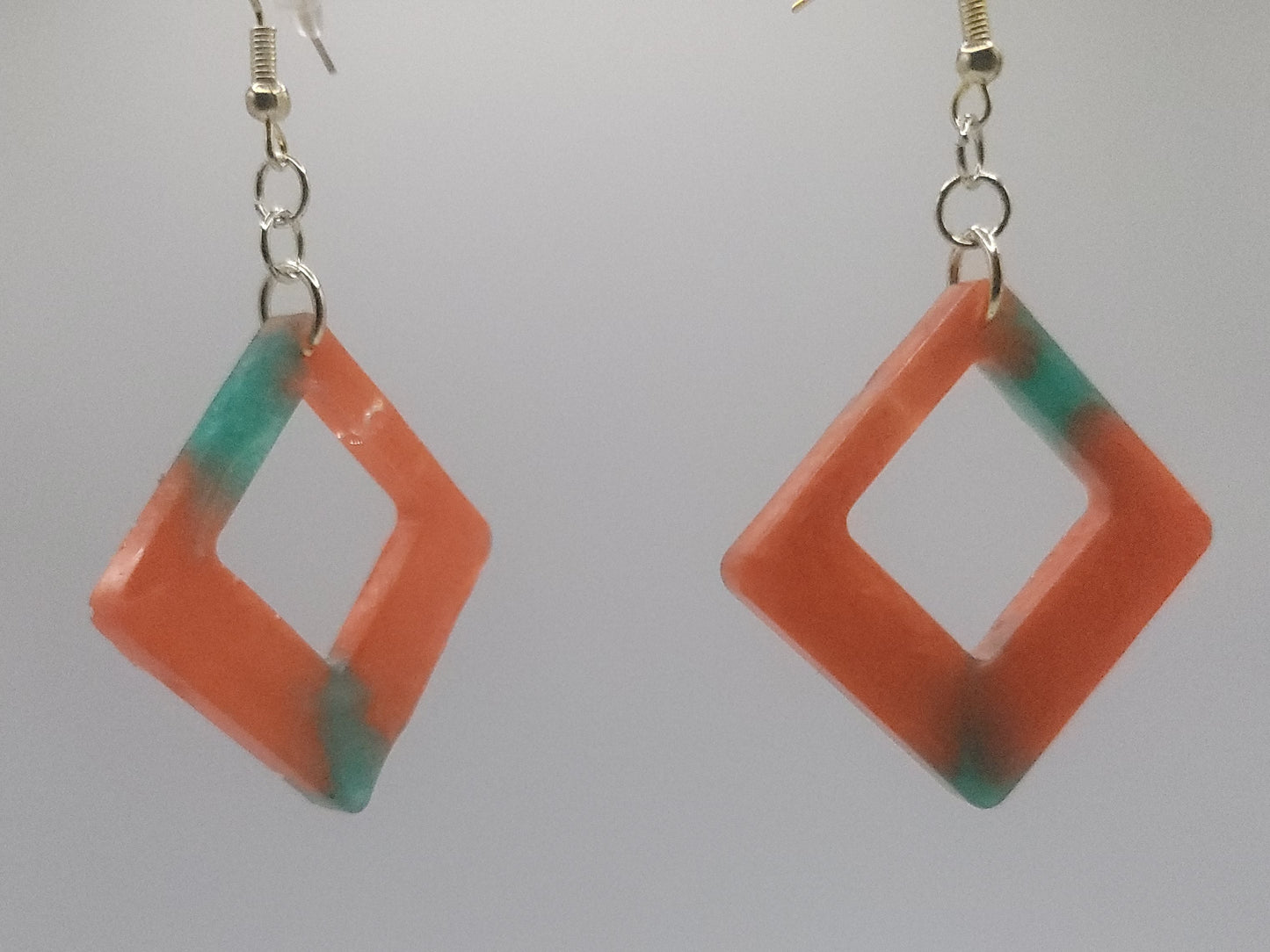 Pair of orange and green diamond-shaped earrings on a white background