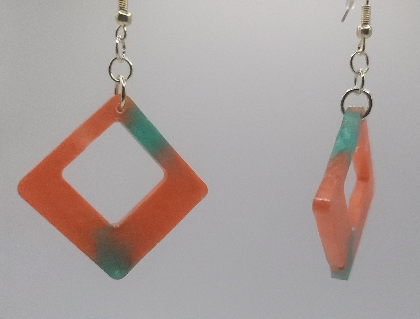Pair of geometric earrings with orange and green gradient on a white background