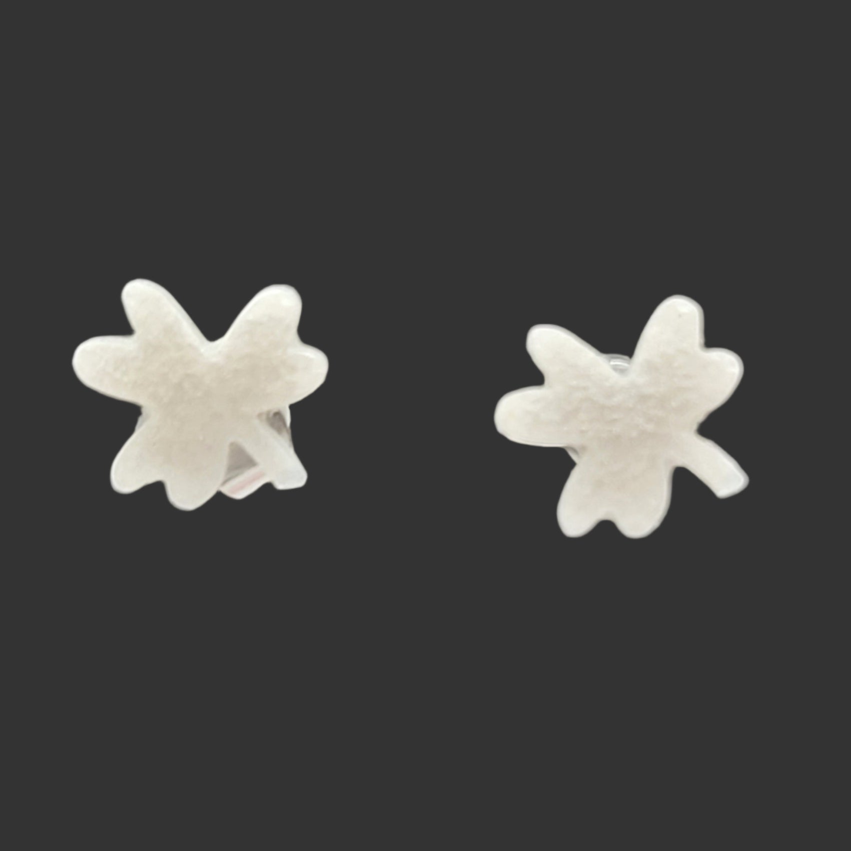 Pair of silver clover-shaped earrings on a black background